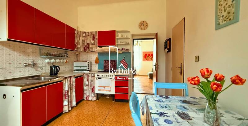 A kitchen in a family house with red cabinets, a table, and flowers in a vase.