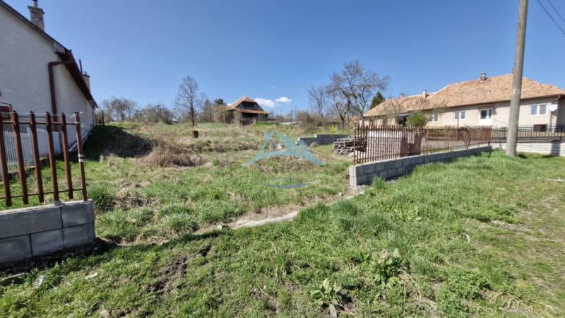 A plot for residential use in Obeckov with a grassy area and neighboring houses.