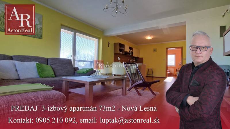 Living room in a holiday apartment with a sofa, table, and kitchenette.