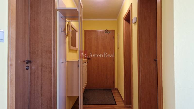 A corridor with wooden doors, yellow walls, and a coat rack system in a Holiday Apartment.