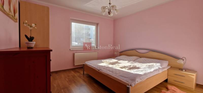 Bedroom in a Holiday Apartment with wooden floor, pink walls, and a bed.