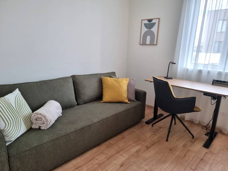 Living room in a 3-room apartment with a sofa, desk, and chair.