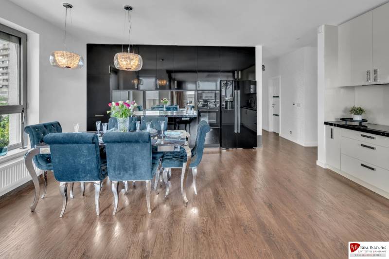 A kitchen in a 4-room apartment with dark cabinets, a dining table, and wooden flooring.