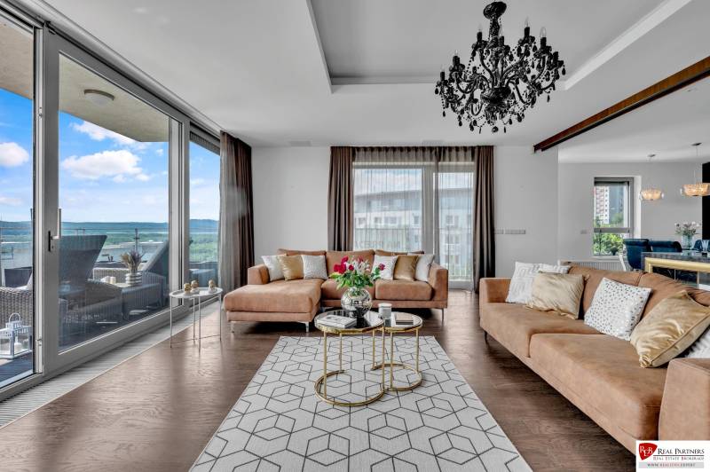 A stylish living room in a 4-room apartment with a sofa, chandelier, and a view of the terrace.