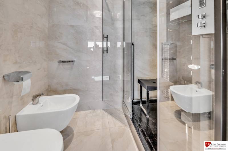 A bathroom in a 4-room apartment with a shower, bidet, and glossy tiles.
