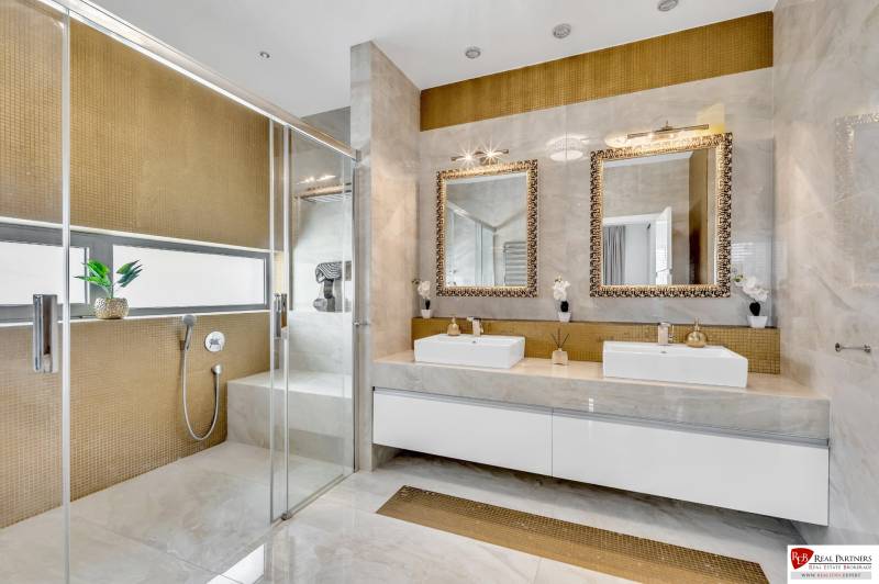 A luxurious bathroom with two sinks, mirrors, and a shower in a 4-room apartment.