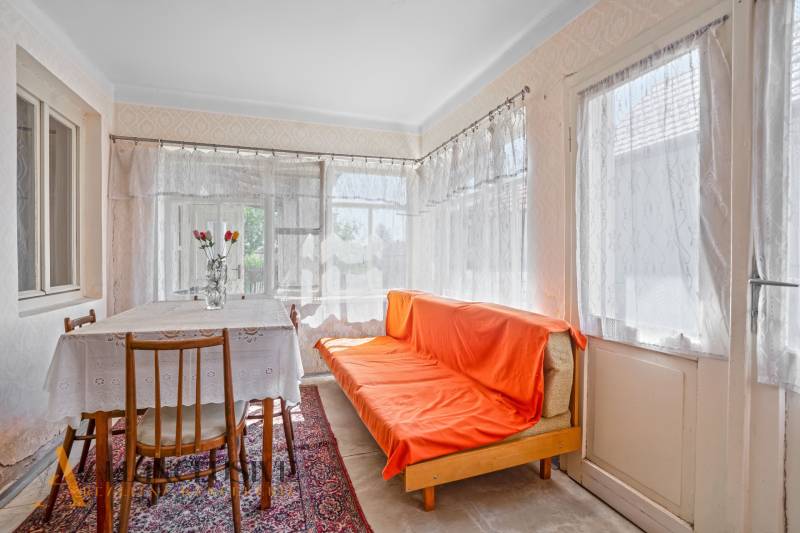 Interior of a family house with a sofa, dining table, and floral decoration in a vase.