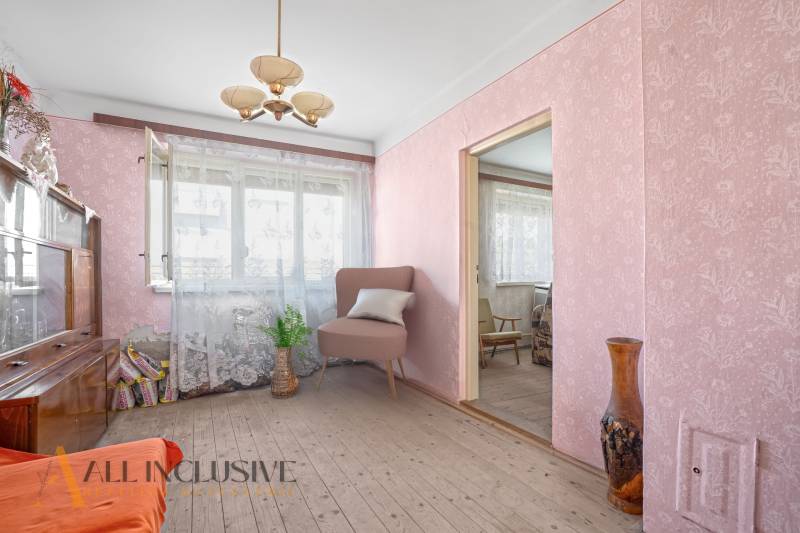 A room in a family house with wallpaper, an armchair, and floral decorations.