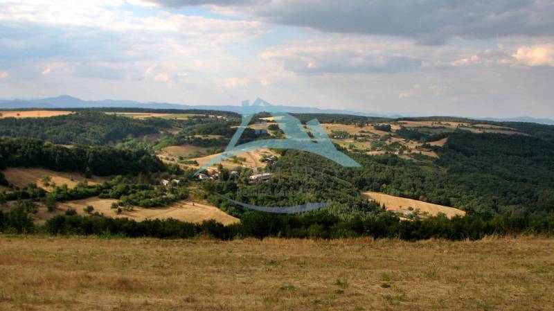Hilly landscape with forests and open spaces, ideal for rural living.
