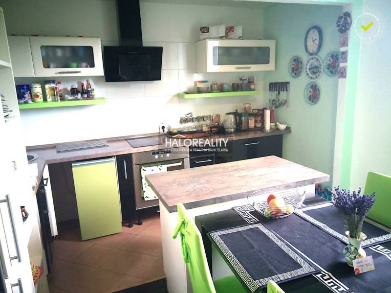 A kitchen in a family house with green and white cabinets and a dining table.