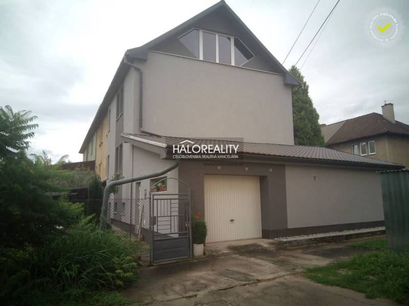 A family house in Nováky with a garden and a garage, surrounded by greenery.