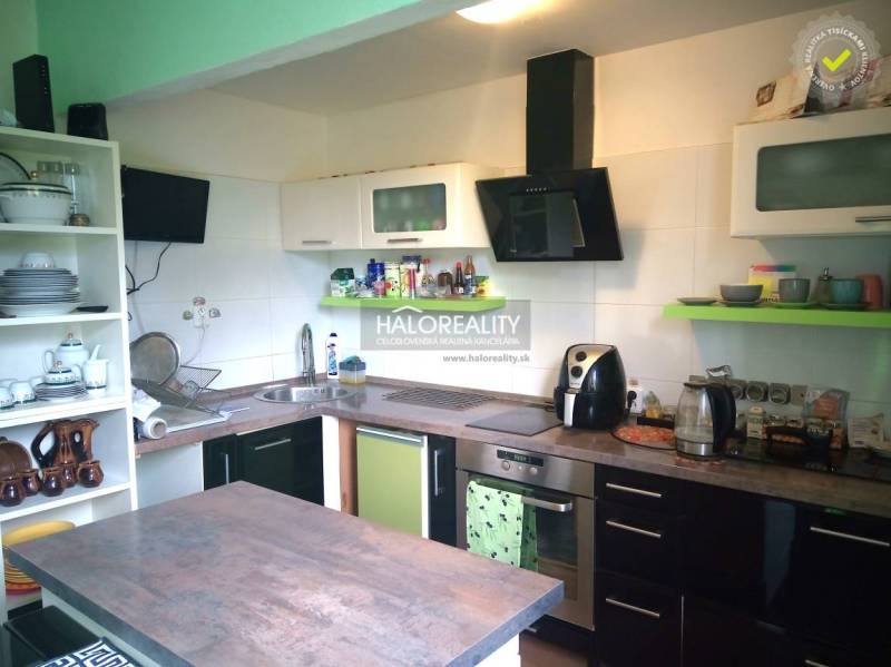 A kitchen in a family house with shelves, appliances, and an extractor hood.