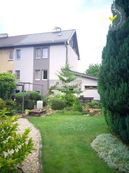 A garden at a family house in Nováky with trees and a gravel path.