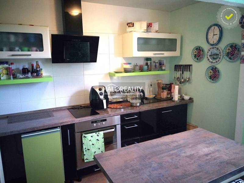 A kitchen in a family house with appliances, hanging plates, and cabinets with shelves.