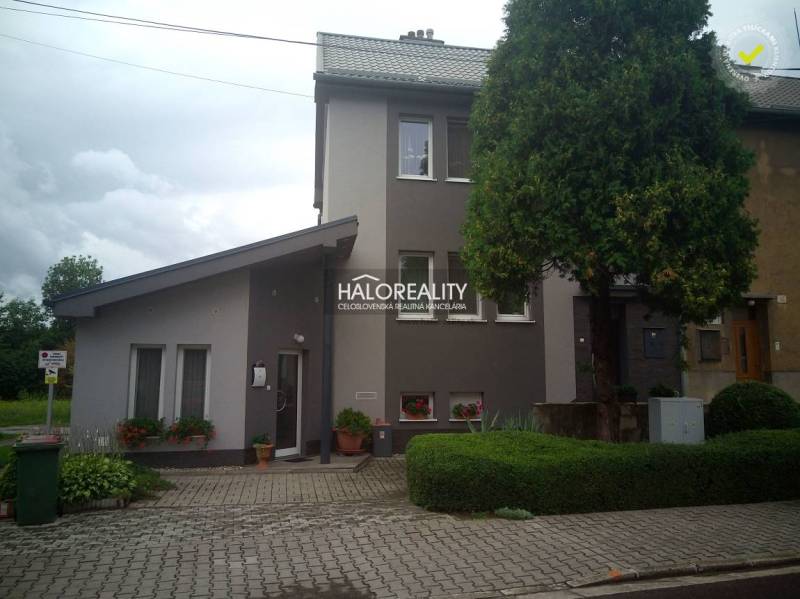 A family house in Nováky with a tree, a garden, and a paved walkway in front of the entrance.