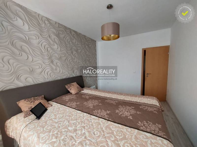 A bedroom in a 3-room apartment with patterned wallpaper and beds with blankets.