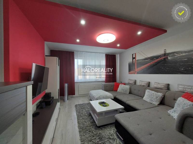Living room in a 3-room apartment with a sofa, TV, and red decorations.