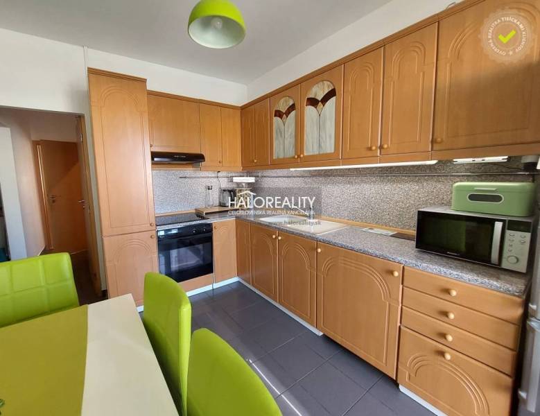 A kitchen in a 3-room apartment with a wooden cabinet and green chairs.