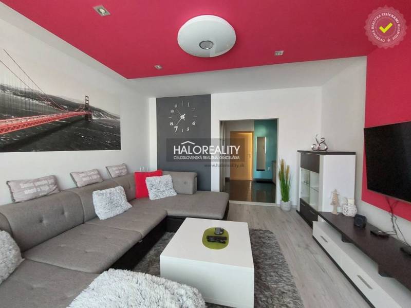 A living room in a three-room apartment with a gray sofa, a red ceiling, and modern furniture.