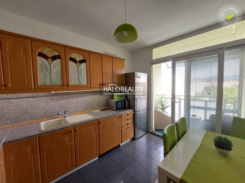 A kitchen with a wooden cabinet in a 3-room apartment, with access to a balcony.