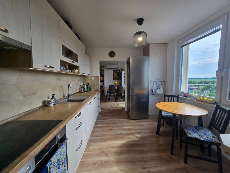 A kitchen in a 4-room apartment with light wooden furniture and a view from the window.