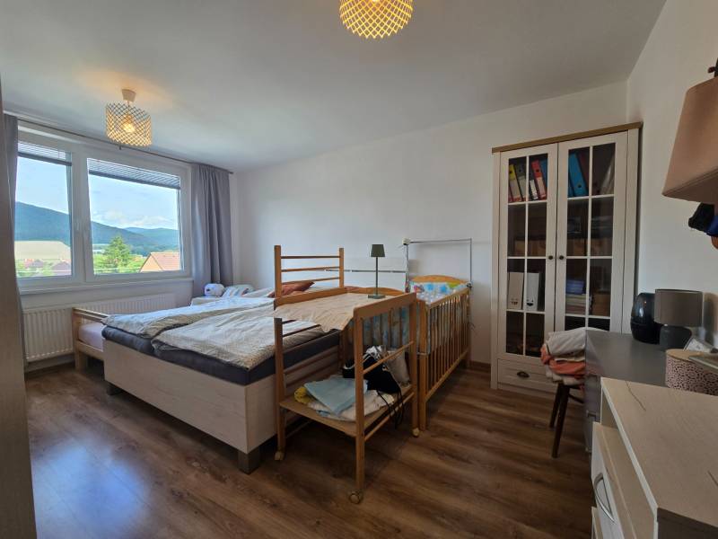 Bedroom with a wardrobe, crib, and view from a 4-room apartment.
