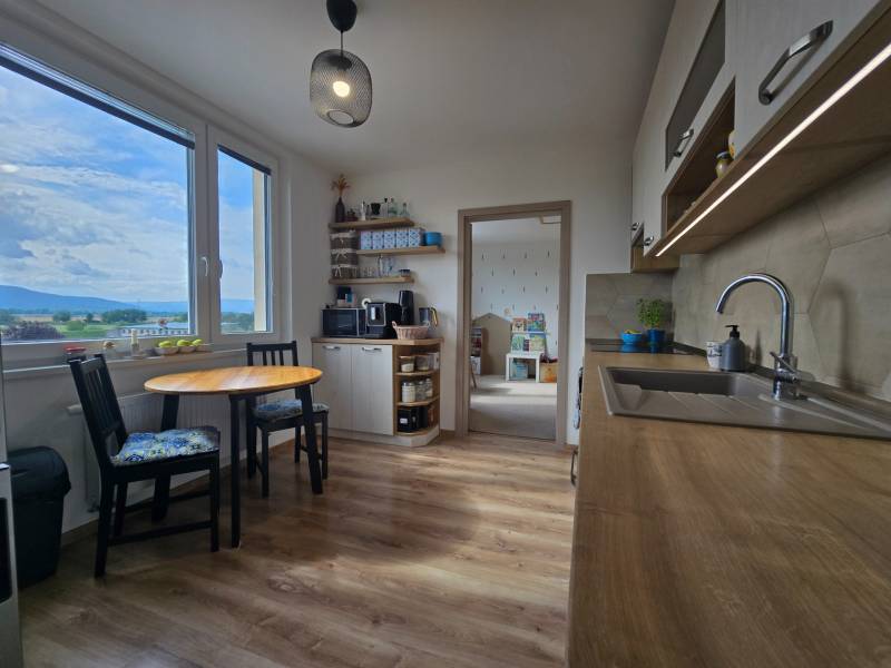 A kitchen in a 4-room apartment with light seating and a view of the surroundings.