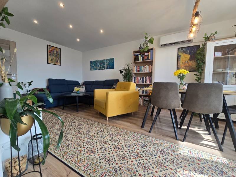 Living room in a 4-room apartment with a sofa, yellow armchair, and wooden furniture.