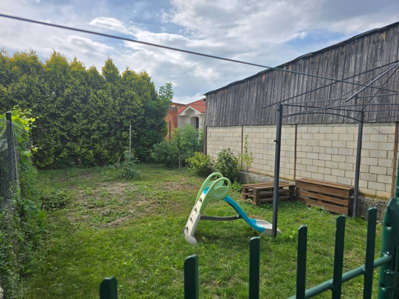 The garden of a 4-room apartment in Kočovce with a swing and greenery.