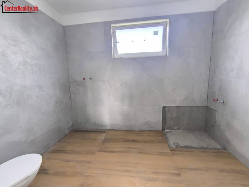 A bathroom in a family house with tiles, ready for installation, light through a small window.
