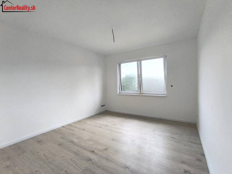 The interior of a room in a family house with white walls and light wood flooring.