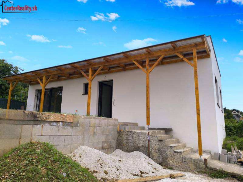 The family house in Malé Krštenany has a white facade and a wooden shelter.