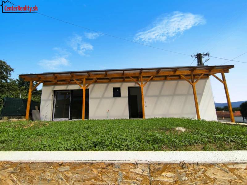 A family house in Malé Kršteňany with a wooden pergola and a lawn on a slope.