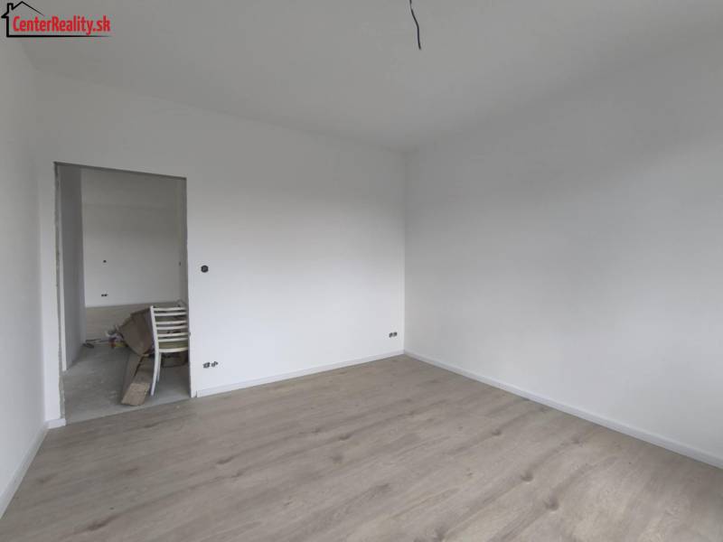 Empty room with white walls and light wooden flooring in a family house.