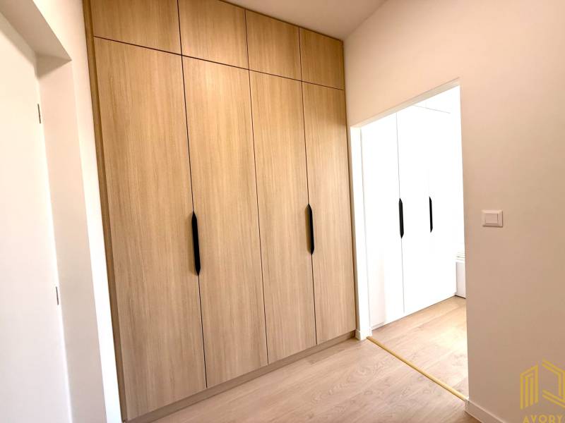A studio apartment with wooden built-in wardrobes and white walls feels cozy.