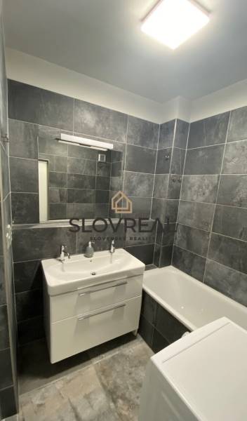 A bathroom with gray tiles and white sanitary ware in a 4-room apartment.