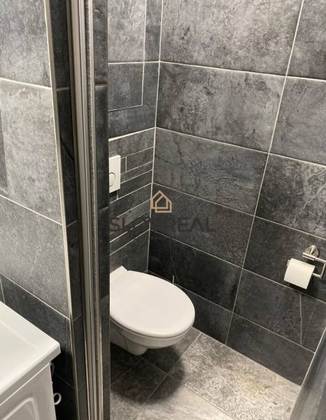 Bathroom in a 4-room apartment with dark gray tiles and a toilet.