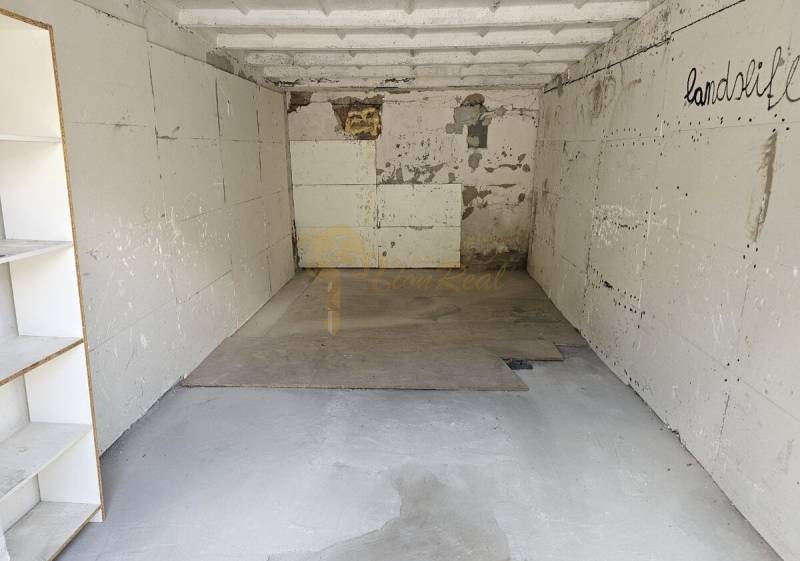 An empty garage interior with walls and shelves, with cracked plaster.