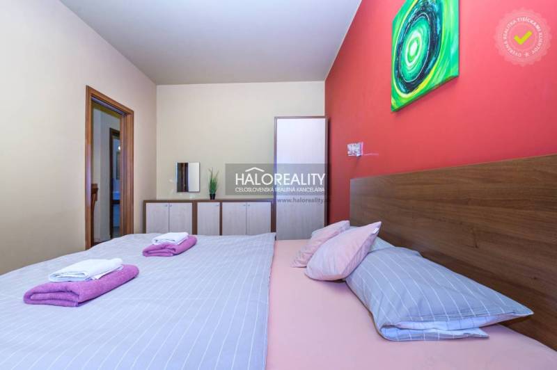 Bedroom with a double bed and an artistic painting in a 2-room apartment.