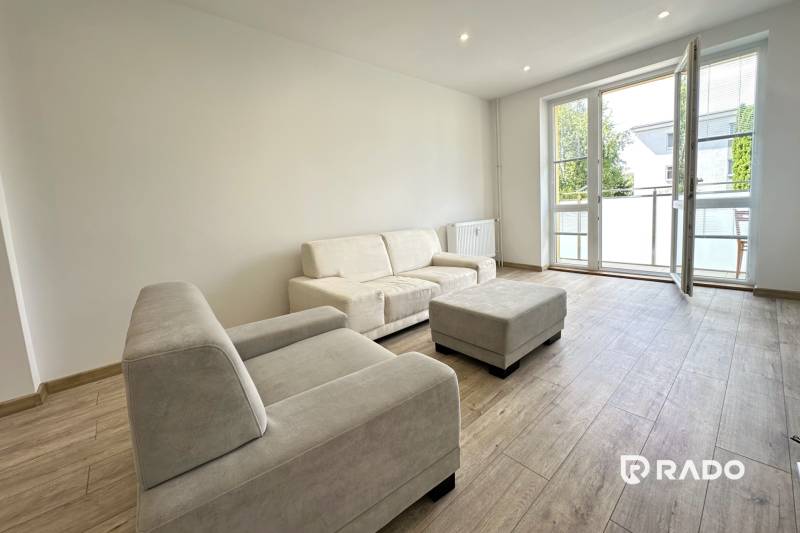 Bright living room in a 2-room apartment with a sofa and a large window.