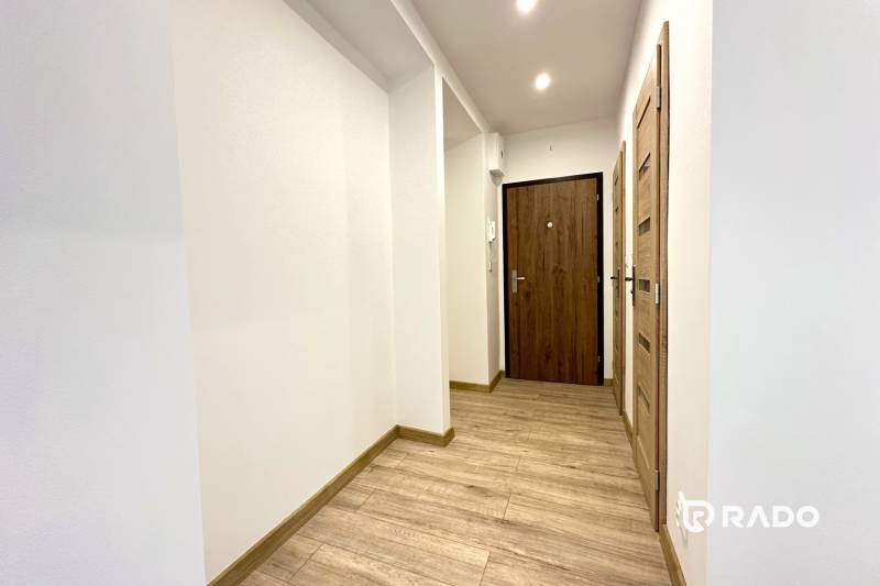 Hallway in a 2-room apartment with wooden flooring and white walls.