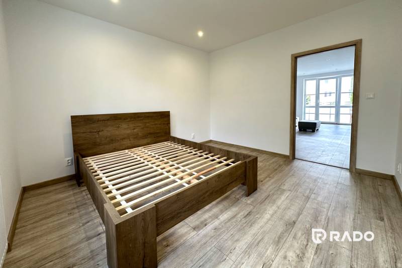 Bedroom in a 2-room apartment with wooden flooring and a bed without a mattress.