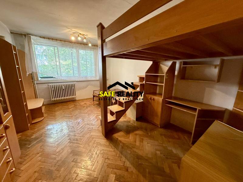 Room in a one-bedroom apartment with a bunk bed, wooden floors, and furniture.