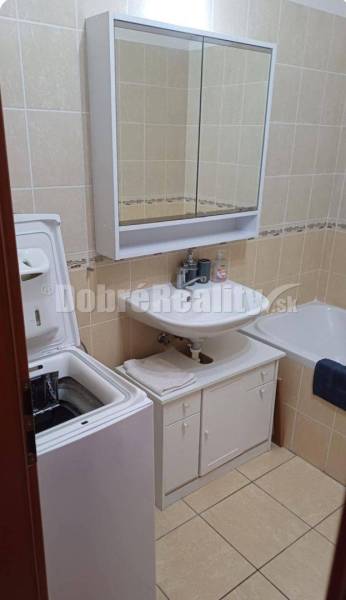 Bathroom with a sink, cabinet, bathtub, and washing machine in a 2-room apartment.