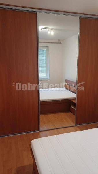 Bedroom with wooden floor and wardrobe in a 2-room apartment.