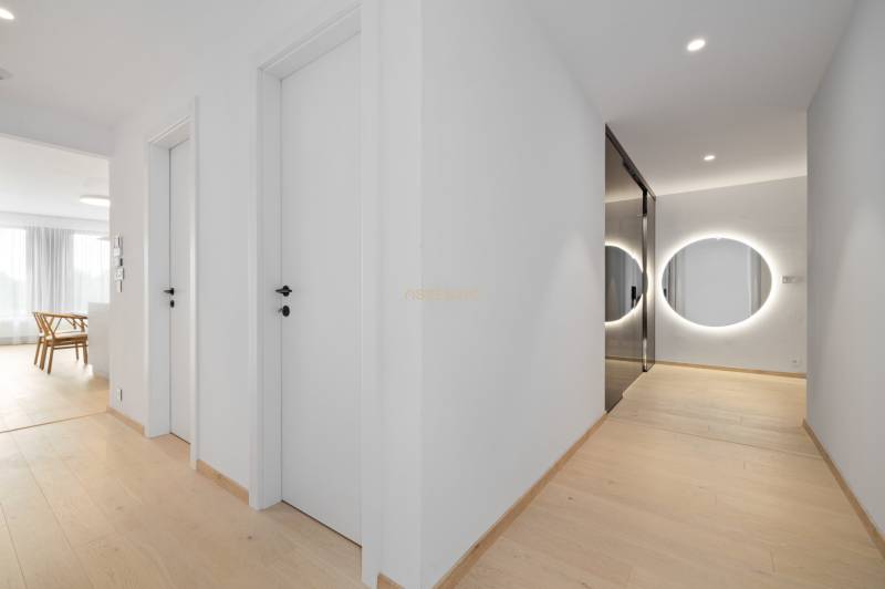 A hallway with a wooden floor, a round mirror, and white doors in a 2-room apartment.