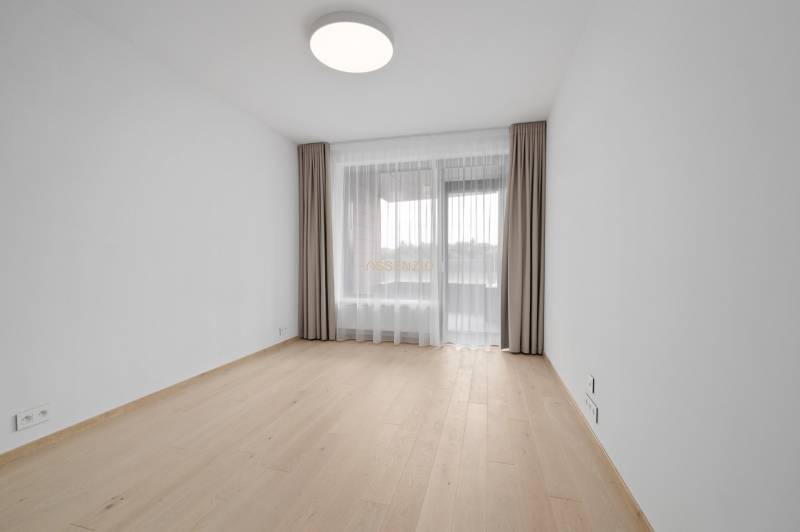 An empty room with wooden flooring, curtains, and a window in a 2-room apartment.