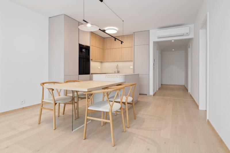 Dining area with stylish chairs and a kitchen in a 2-room apartment.