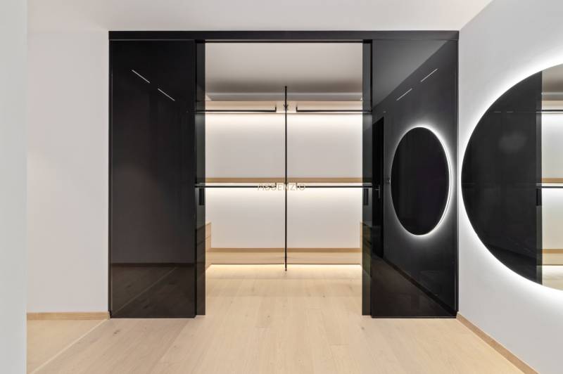 A minimalist wardrobe interior with a mirror and lighting in a 2-room apartment.