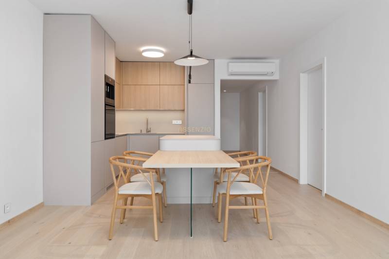 Dining table with four chairs and a kitchen in a 2-room apartment.